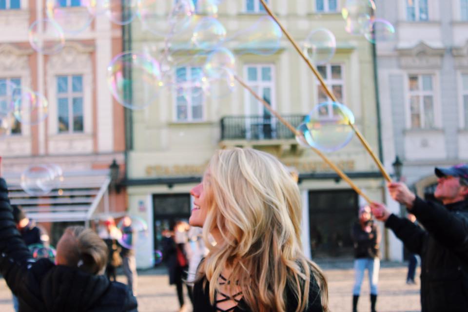 Girl smiling in Prague square with bubbles
