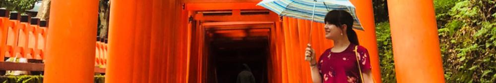 Student walking by Tori Shrines in Japan with umbrella