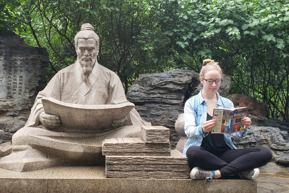 Student reading next to a statue